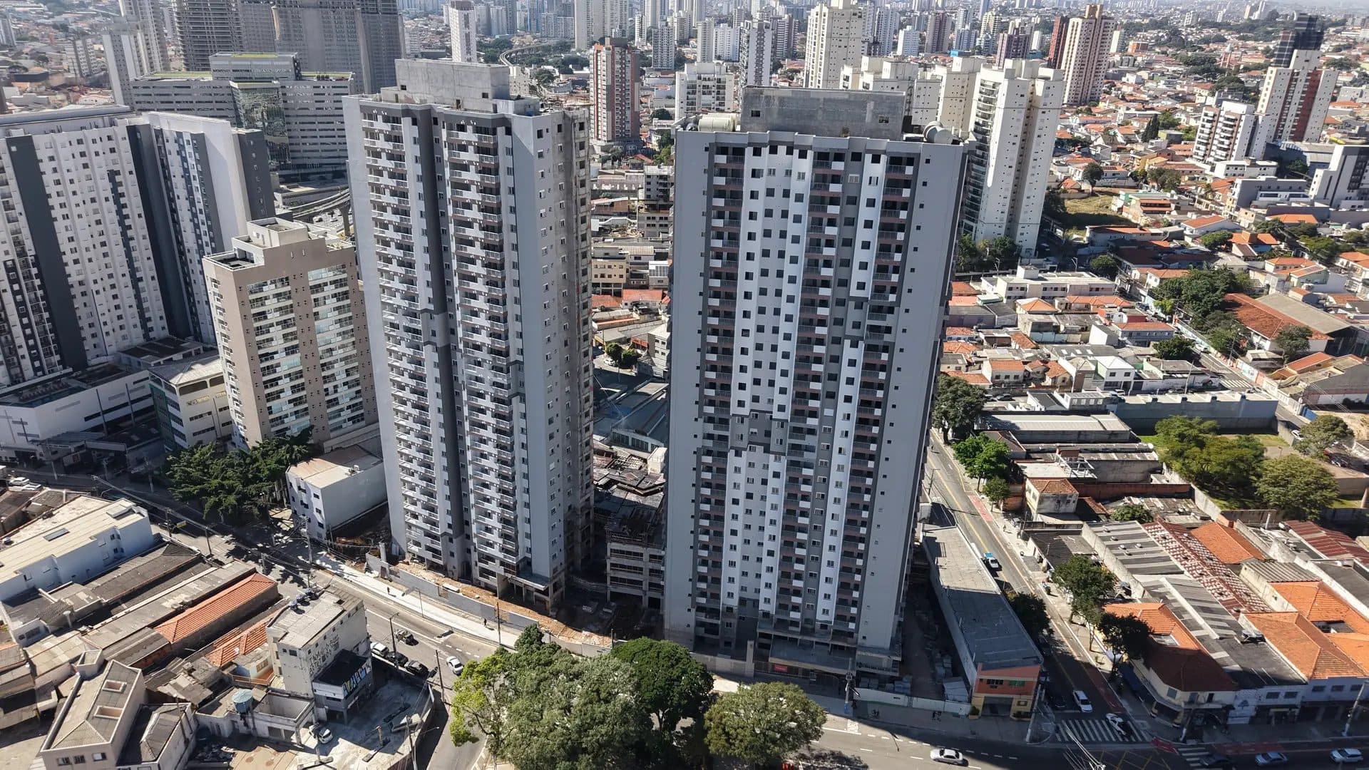 Vista aérea de torres residenciais em construção com entorno urbano.