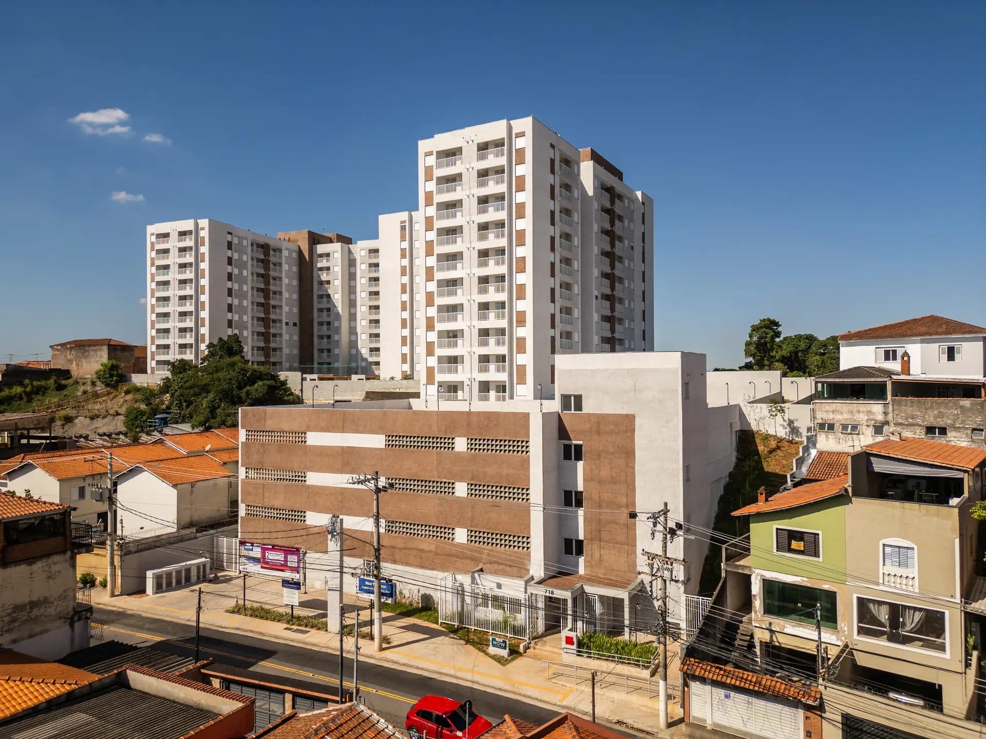 Vista externa da fachada do edifício residencial com estacionamento e entorno urbano