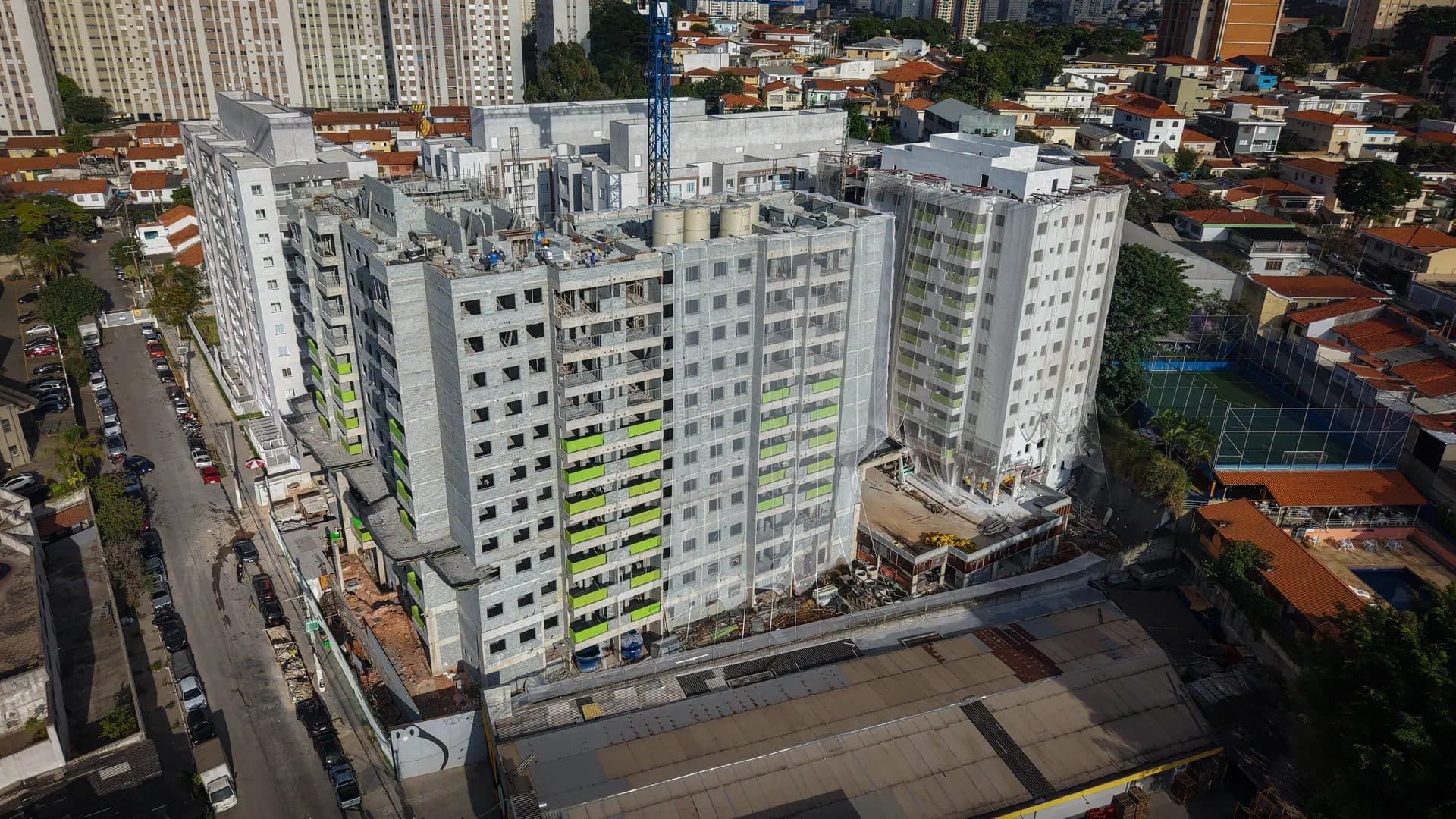 Vista aérea da obra do condomínio com prédios em construção e entorno urbano